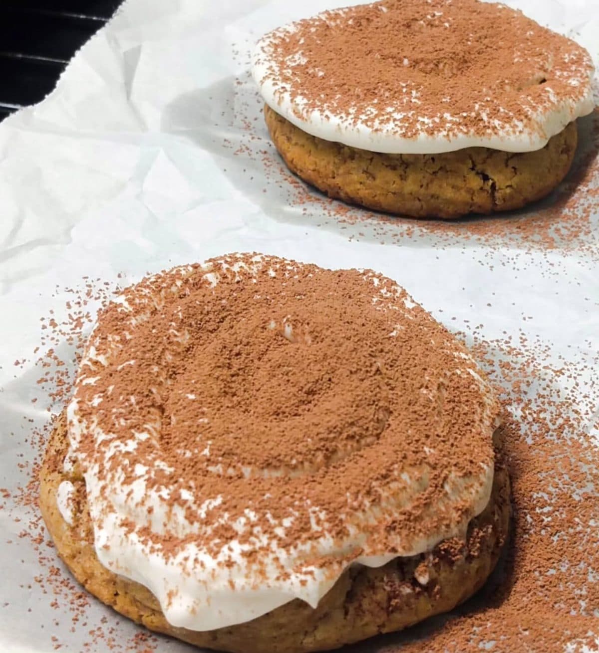 Large cookie cake topped with cream and dusted cocoa